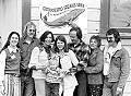 Organizers of the First Annual Mendocino Whale Festival pose outside Crown Hall with J.D. Mayhew's  poster, March 20, 1976. L to R: Ellen Findlay, Bill Wilson, Sue Golden, Brendan, Heidi and Barry Cusick, Sally and Lee Welty.