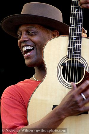 Eric Bibb performs with the Campbell Brothers and flashes a great smile at Carl Campbell, the drummer.