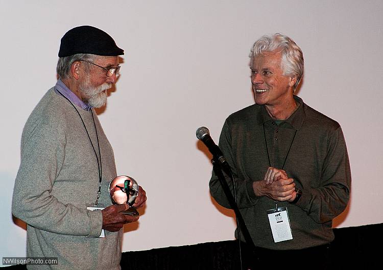 Les Blank holds the 2011 Maysles Award trophy as Bill Nichols applauds.