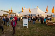 Warm summer evening light bathes the Mendocino Music Festival concert hall tent for the Opening Concert. Festival Manager Nancy Harris is in the foreground wearing sunglasses.
